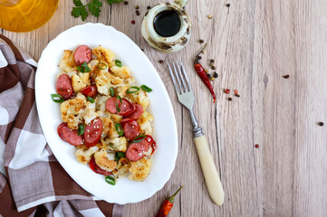 Warm salad of cauliflower, grilled sausages, green onions. A dish of cauliflower. Top view.