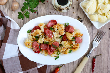 Warm salad of cauliflower, grilled sausages, green onions. A dish of cauliflower. Top view.