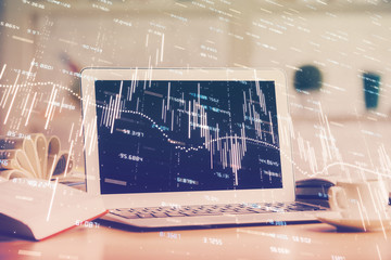 Stock market graph on background with desk and personal computer. Double exposure. Concept of financial analysis.