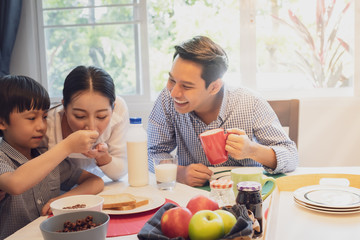 Asian family, father and son having breakfast together with mother in dining room, happy family concept