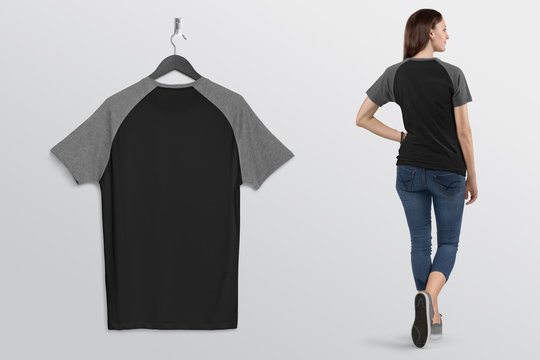 Hanging Plain Black And Grey Raglan T Shirt On Wall. Beside Standing Beautiful Female Model In Blue Denim Jeans Pant. 