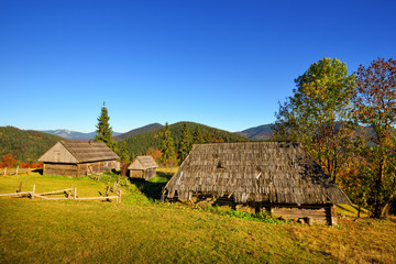 Beautiful landscape with old wooden huts in the Carpathians mountains. Autumn sunny day.