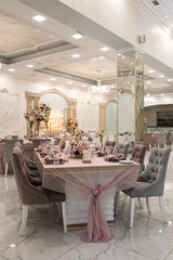 Look from afar at luxurious restaurant hall prepared for wedding dinner