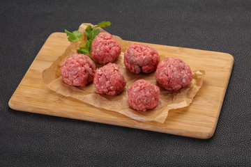 Raw meatball over wooden background