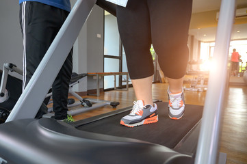leg of fat woman being run or jog on belt of treadmill machine, workout under intruction of trainer