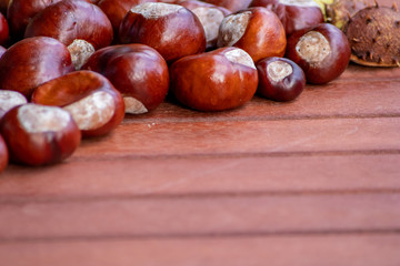 Ein frischer Haufen schöner Kastanien liegt auf einem braunen Tisch bereit zum kreativen Basteln mit Kindern im Herbst und Winter