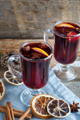 mulled wine in two glasses with fruits and spices on wooden background