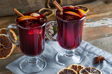 mulled wine in two glasses with fruits and spices on wooden background