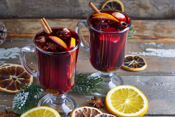 Christmas mulled wine in two glasses with fruits and spices on wooden background