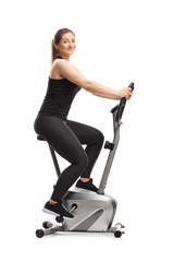 Young woman riding a stationary bike and smiling at the camera