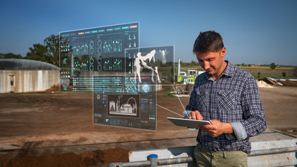 An young agronomist is using a tablet with futuristic augmented reality holograms for controlling a...