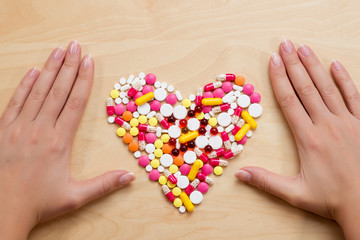 handful of heart-shaped pills and hands on the table
