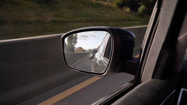 Looking babk in a car's side mirror - concept: travel, trip, reflection, past