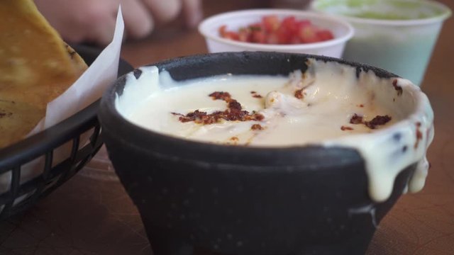 Hand Dipping Chips in Queso Cheese Dip at Mexican Restaurant