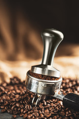 Coffee tamper,coffee press is made of stainless steel and roasted coffee beans from coffee roaster on black background,tool tamper