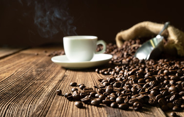 Cup of espresso with coffee beans, bag, scoop and steam