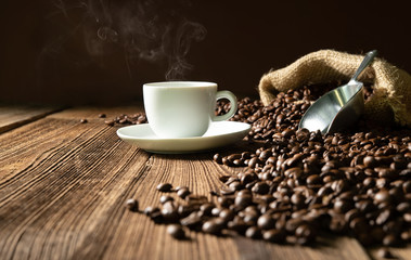 Cup of espresso with coffee beans, bag, scoop and steam