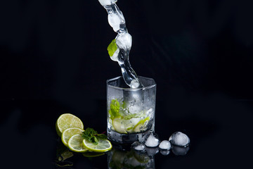 Summer cocktail mojito with splash on black background..