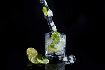 Summer cocktail mojito with splash on black background..