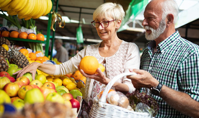 Mature shopping couple with basket on the market. Healthy diet.