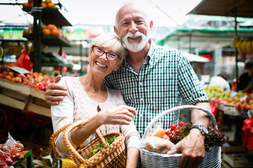 Mature shopping couple with basket on the market. Healthy diet.
