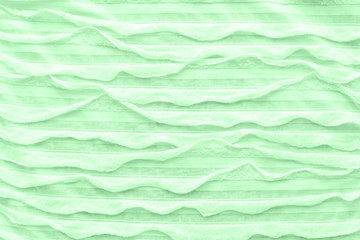Abstract textile background. Neo mint colored fabric with ruche. Top view, flat lay.