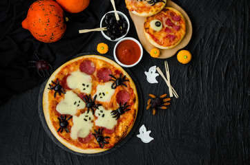 Halloween Pizza Monsters with cheese Ghost and olive Spider on a black background. Food idea for Halloween party.