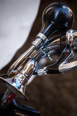 Close-up of a bicycle horn on the handlebar, a small chromed trumpet