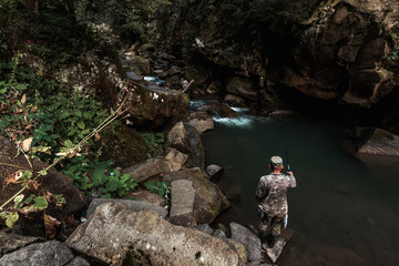 back view of military man fishing and standing on rock