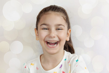 Portrait of happy adorable laughing child girl on light background. Positive emotions.