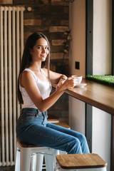 Close up of girl drinking cappuccino in the cafe. Beautiful brunette