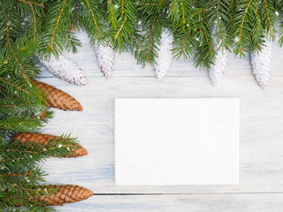 Fir tree branch with cones, tablet, snowflake on white wooden background. Christmas and New Year concept