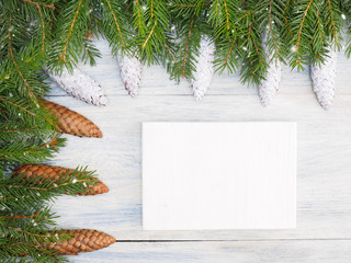 Fototapeta na wymiar Fir tree branch with cones, tablet, snowflake on white wooden background. Christmas and New Year concept