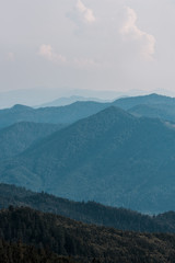 mountains with green trees against sky with clouds