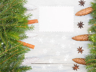 Fir tree branch with cones, cinnamon, anise, nameplate, snowflake on white wooden background. Christmas and New Year concept