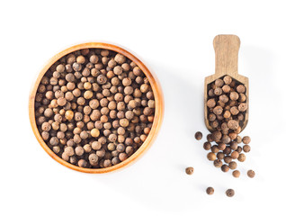 Allspice (Jamaica pepper) in wooden cup and scoop on white background