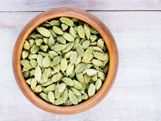 Spice Green cardamom (Elettaria cardamomum) in a wooden cup on a brown wooden background