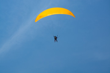 Skydiver with a yellow parachute on a background of blue clear sky