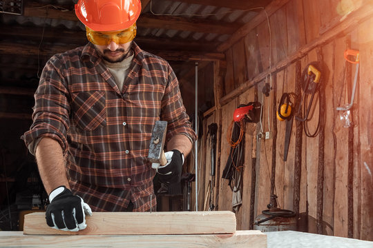 A Man Carpenter Hammer A Nail Into A Tree, Male Hands With A Hammer Close-up. Woodwork