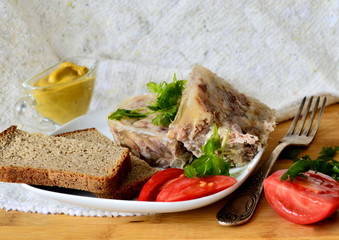 Jelly with meat, beef jelly, traditional Russian dish, serving on a plate, mustard, bread, tomatoes. Side light. Close-up.