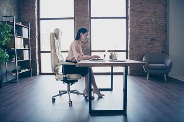 Full length body size photo of concentrated serious executive director creating annual plan for her corporation sitting in front of digital device wearing spectacles