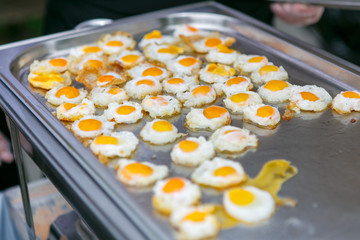 A lot fried quail eggs in the metal container
