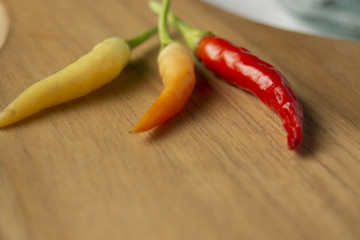 Red Chili Peppers, orange and yellow on wooden cutting board.
