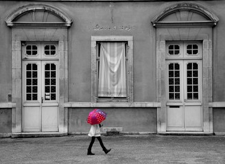 enfant marche avec un parapluie devant en bâtiment