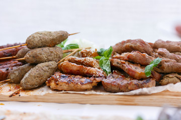 A front view of meaty barbeque with lula kebabs and mint leafs