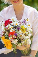A young woman in striped blouse is holding flower bouquet