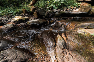 sunshine on flowing river near wet stones in park