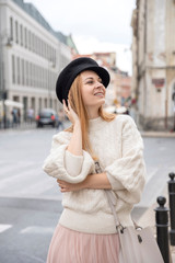 Fototapeta premium Cute cheerful caucasian woman walking on european street. She wear stylish outfit.