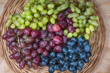 fresh juicy berries of different grapes on a wicker wooden surface