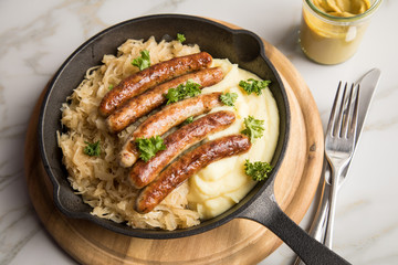 Kleine Bayrische Nürnberger Rostbratwürste mit Sauerkraut, Kartoffelpüree und Senf in rustikaler...